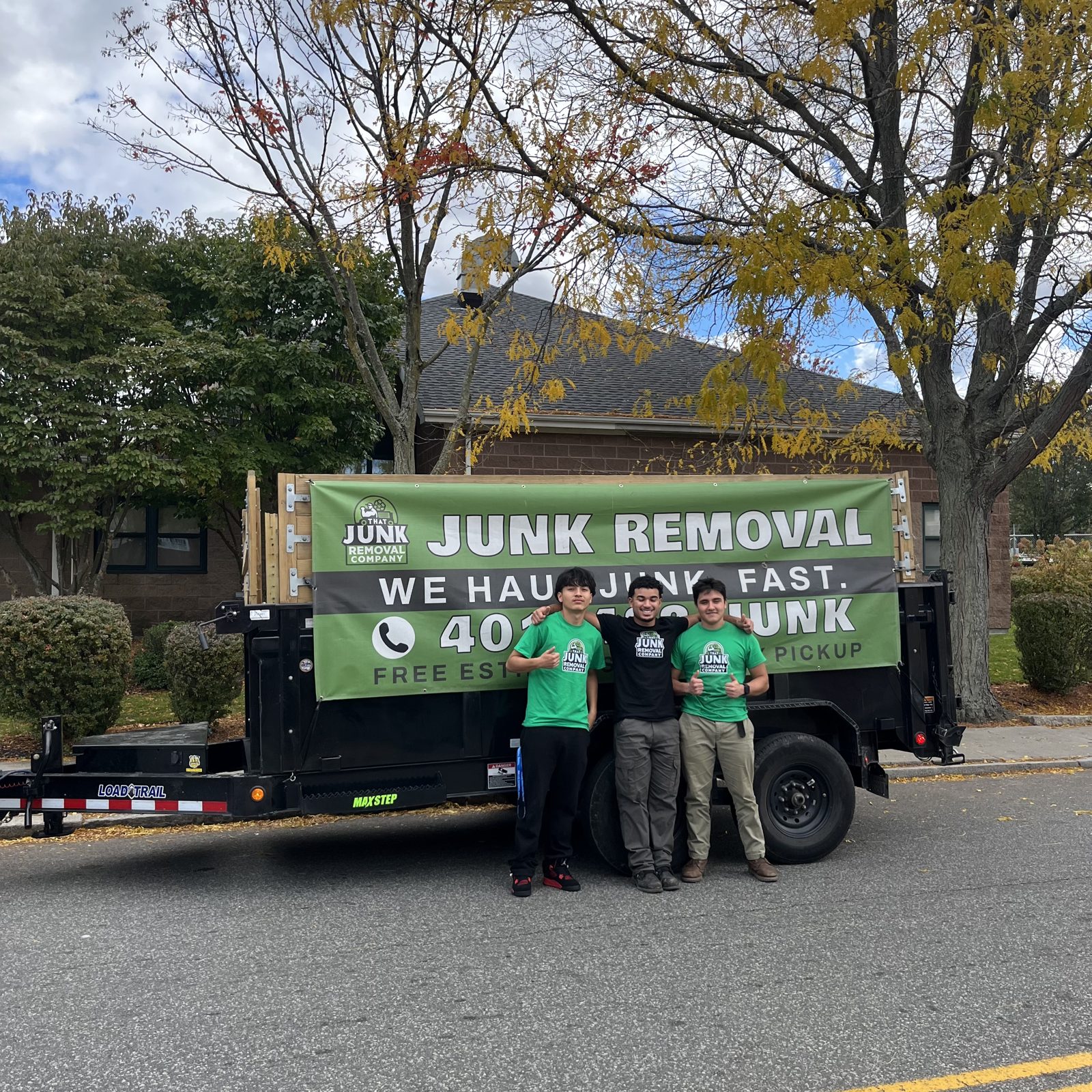 The crew standing with their truck and junk removal banner on a residential street